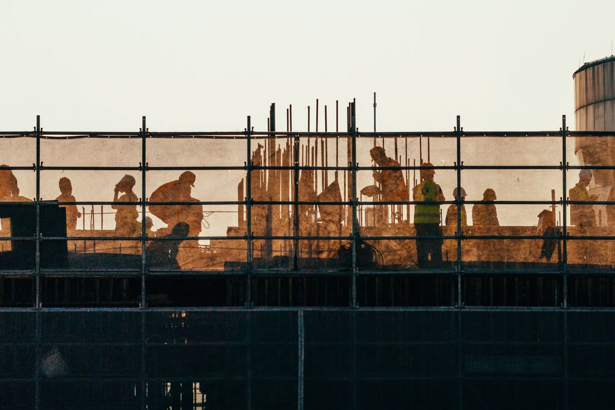 Construction workers silhouetted behind scaffolding at golden hour
